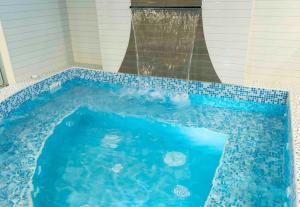 利马Hospedaje Las Tres Regiones的一座房子里带瀑布的蓝色游泳池