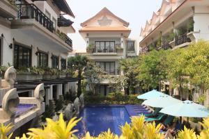 暹粒Khmer Mansion Residence的享有酒店的景致,设有游泳池和遮阳伞
