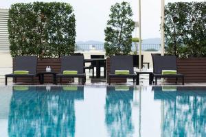 清迈Centara Riverside Hotel Chiang Mai的一个带两把椅子、一张桌子和一张桌子的游泳池