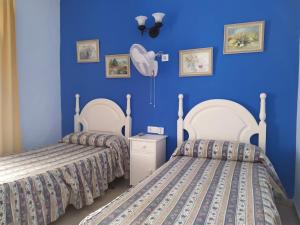 圣玛丽亚港Hostal Manolo的蓝色墙壁客房的两张床
