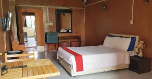 曼那โรงแรมวินบางนา Win Bangna Hotel的一间卧室配有一张床、一张桌子和一台电视