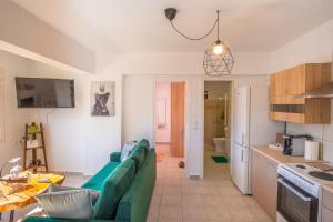 普拉曼塔Remvi GUEST HOUSE的一间带绿色沙发的客厅和一间厨房
