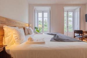 辛特拉卡萨达潘多酒店的卧室配有一张白色大床,上面有毛巾