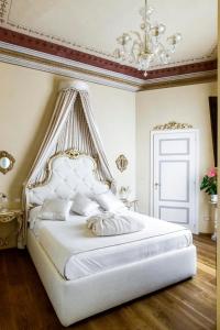 锡耶纳Residenza d'Epoca Palazzo Borghesi的白色卧室配有一张带吊灯的大床