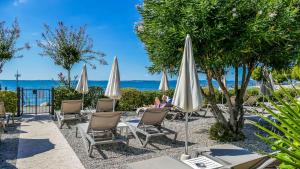 巴多利诺莱蒂齐亚别墅酒店的一个带椅子和遮阳伞的庭院和大海