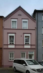 盖尔森基兴SK Apartments - Liborius的一座粉红色的房子,前面有一辆面包车