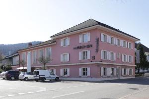 迪格滕兰德格斯霍夫赫尔森酒店的一座粉红色的建筑,前面有汽车停放