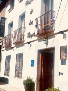 托莱多Alda Hospedería De Los Reyes的白色的建筑,设有两个阳台和门