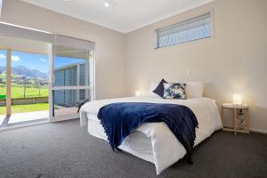 怀希比奇Sky Blue Retreat - Waihi Beach Holiday Home的白色的卧室设有床和大窗户