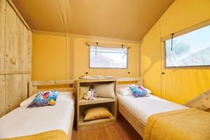 乌马格Camping Park Umag Glamping的配有黄色墙壁的小客房内的两张床