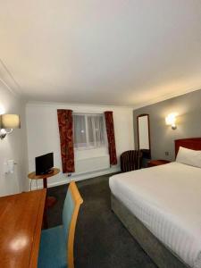 坎诺克Roman Way Hotel的酒店客房设有一张床、一张书桌和窗户。