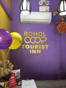 塔比拉兰Bohol Coop Tourist Inn的一间设有紫色墙壁、标志和气球的房间