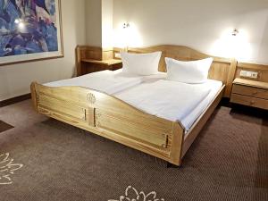 韦特海姆尹登赫恩维森酒店的一间卧室配有一张带白色床单和枕头的木制床。