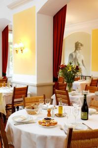 尼翁克伦贝特酒店的一间设有白色桌椅和雕像的餐厅