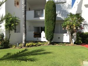 EsteponaApartment Costalita, direct beach access, ground floor, salt water pool的一座白色的房屋,有树木和院子