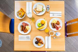 诺里奇快捷假日诺威奇酒店的一张木桌,上面放着早餐盘
