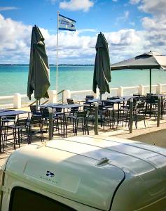 圣特罗让莱班Le Homard Bleu的海滩上一组桌椅和遮阳伞