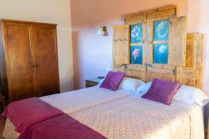 La Mata de los OlmosCasa Rural Bonal的一间卧室配有一张带紫色枕头的大床