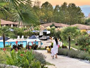 桑丹斯基Medite Spa Resort and Villas的一名在度假村游泳池边白色散步的女人