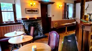 达农The Coylet Inn by Loch Eck的一间带桌椅和壁炉的餐厅