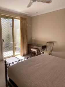 伊丘卡阿卡夏露台别墅的一间卧室配有一张床、一张书桌和一个窗户。