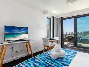 凯阿玛Sebel Harbourside 301 Kiama的酒店客房配有一张床和一张书桌及一台电视
