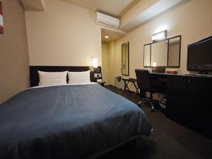 水户美图县厅前旅途酒店的酒店客房设有一张床、一张书桌和一台电视机。
