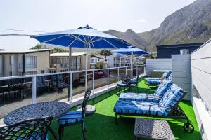赫曼努斯Whale Coast Ocean Villa的阳台配有桌椅和雨伞。