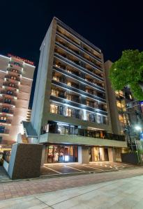 福冈MK Hotels Nishinakasu的一座高大的建筑,晚上有灯