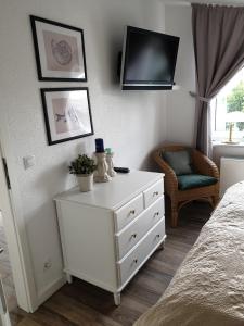 朱列斯拉赫Ferienwohnung Muschelsucher的卧室配有白色梳妆台和墙上的电视
