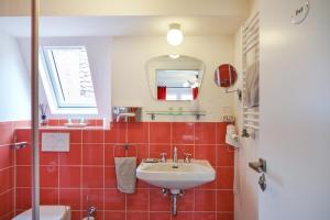 奥伯德尔丁根Pension Amthof的红色瓷砖浴室设有水槽和镜子