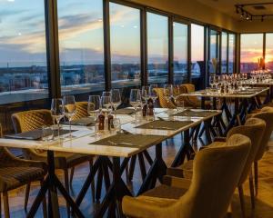 布加勒斯特Union Plaza Hotel的餐厅设有长桌子、椅子和窗户。