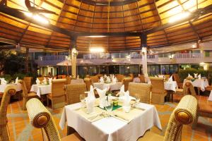 芭东海滩Palmyra Patong Resort Phuket - SHA Extra Plus的餐厅设有白色的桌椅和大型天花板。