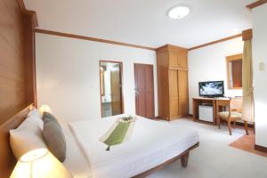 芭东海滩Palmyra Patong Resort Phuket - SHA Extra Plus的卧室配有白色的床和电视。