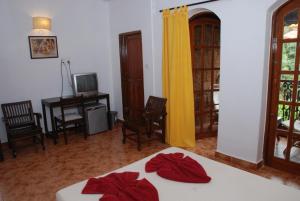 坎多林Sea Breeze Beach Resort Candolim, Goa的一间卧室配有一张床、一张书桌和一台电视