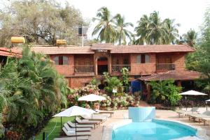 坎多林Sea Breeze Beach Resort Candolim, Goa的一个带游泳池和椅子的度假胜地和一座建筑
