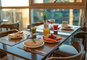 巴西利亚Flat Hotel Fusion com Varanda & Garagem A219的餐桌,带食物盘和橙汁杯