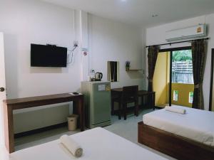 攀牙Rachawadee House的客房设有两张床、一台电视和一张书桌。