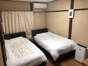 京都雅顺旅馆的配有白色床单的客房内的两张床
