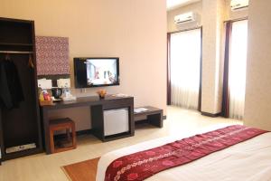 Banjarbaru罗迪萨班亚尔巴鲁酒店的一间卧室配有一张床和一张书桌及电视