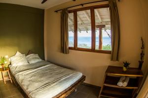 坎布塔尔Hotel Kambutaleko的一间卧室设有一张床和一个海景窗户