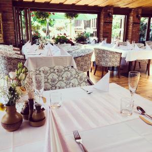 特伦钦Maria Penzion & Restaurant的餐厅配有白色桌椅和白色桌布