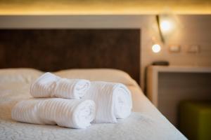 托尔博莱Hotel Garnì Villa Magnolia的三条滚毛巾,坐在床上