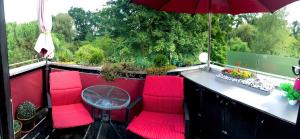 代德斯海姆Ferienwohnungen Deidesheim的阳台配有红色椅子、桌子和雨伞。