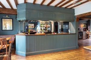 AshburyThe Rose & Crown, Ashbury的餐厅内拥有蓝色墙壁和木地板的酒吧