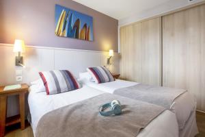比亚里茨Résidence Pierre & Vacances Premium Haguna的配有两张床铺的酒店客房 - 带一双鞋