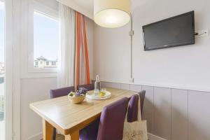 比亚里茨Résidence Pierre & Vacances Premium Haguna的一张带紫色椅子的餐桌和一台平面电视