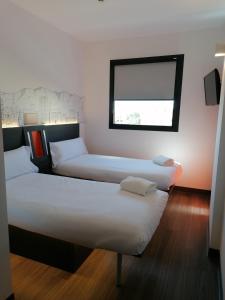 马拉加easyHotel Malaga City Centre的带窗户的客房内的两张床