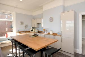 佩恩顿Loveliest Homes Paignton - Wavecrest Apartments - mixed sizes - parking的厨房配有木桌和冰箱。