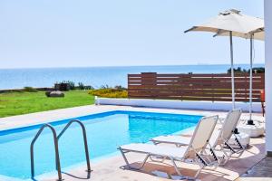 PlimmiriNerida Beachfront Villas的一个带两把椅子和遮阳伞的游泳池